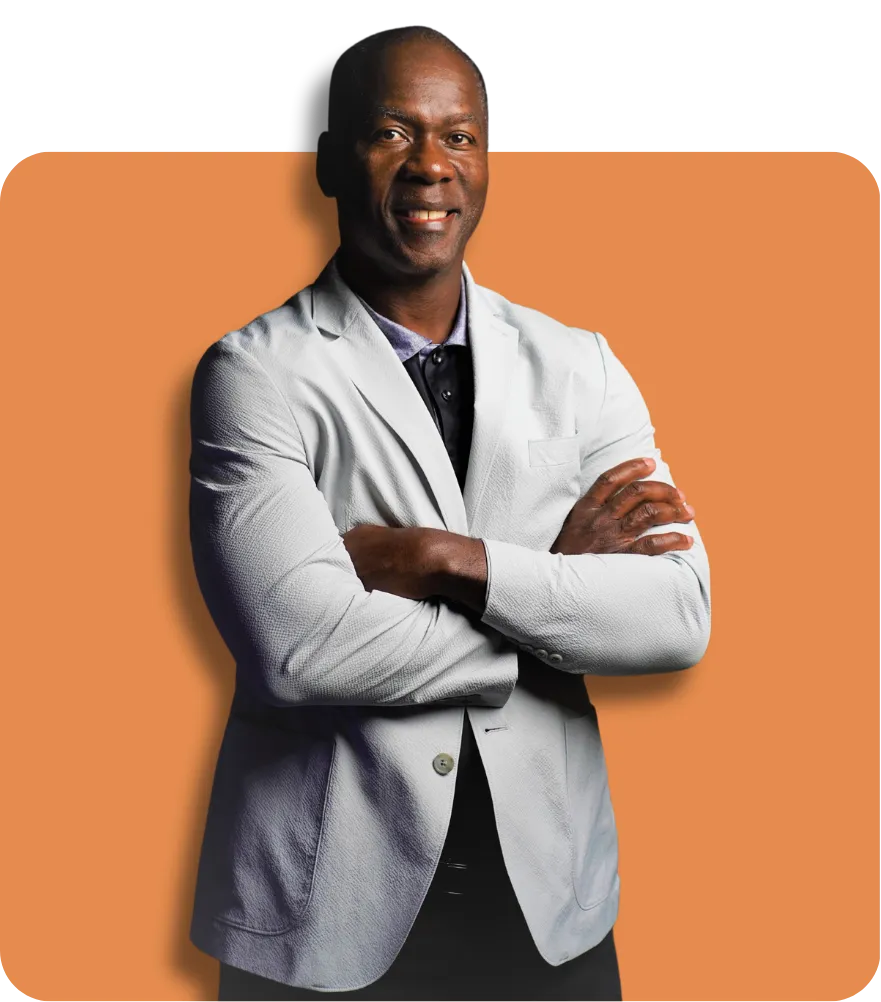 Man in a gray blazer and dark shirt, arms crossed, against an orange background